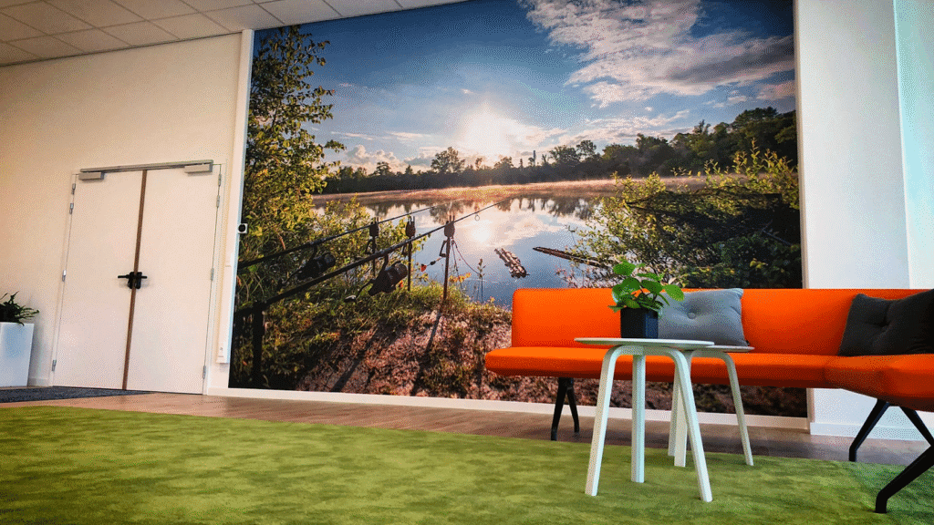 wachtruimte met groen tapijt, oranje bank en textielframe met daarop een landschap