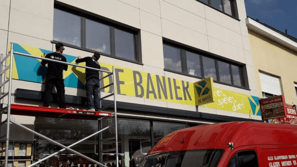 Werkmannen op stelling die gevelreclame plaatsen 